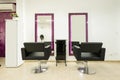 black leather sofas in a beauty salon with rectangular mirrors on the wall with a black cabinet in between Royalty Free Stock Photo