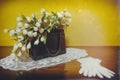 Black leather vintage purse filled with flowers standing on glass surface with white lace gloves like decoration Royalty Free Stock Photo