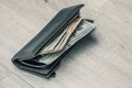 Black leather wallet with american dollars on a gray wooden floor background, close-up with copy space. Full of money. Development Royalty Free Stock Photo