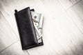 Black leather wallet with american dollars on a gray wooden floor background, close-up with copy space. Full of money. Good Royalty Free Stock Photo