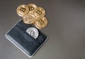 The black leather wallet on a dark background with several gold and silver bitcoins falling out of their pockets.