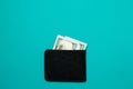 Black leather wallet with dollar bills on blue background. Men`s purse with money bills Royalty Free Stock Photo