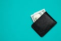 Black leather wallet with dollar bills on blue background. Men`s purse with money bills Royalty Free Stock Photo