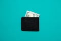 Black leather wallet with dollar bills on blue background. Men`s purse with money bills Royalty Free Stock Photo