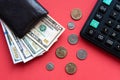 black leather wallet with dollar bills of different denominations, coins and a calculator on a red background Royalty Free Stock Photo