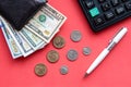 black leather wallet with dollar bills of different denominations, coins, a pen and a calculator on a red background Royalty Free Stock Photo