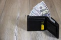 Black leather wallet with dollars and a credit card inside on a gray wooden table Royalty Free Stock Photo