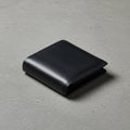 Black leather wallet with a smooth texture on a gray concrete surface. The wallet is Royalty Free Stock Photo