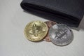 Black leather wallet on table with coins of bitcoins falling out of their pockets. The concept of crypto currencies