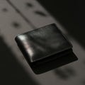 Black leather wallet with textured surface on dark background with shadow Royalty Free Stock Photo