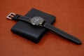 Black leather watch on black wallet with brown background closeup view Royalty Free Stock Photo