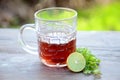 The black lemon tea in the glass cup with anise and lemon on the brown green background