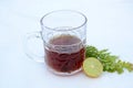 The black lemon tea in the glass cup with anise and lemon on the white background
