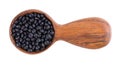 Black lentils in wooden spoon, isolated on white background. Dry beluga lentil grains pile. Top view. Royalty Free Stock Photo