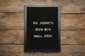 Black letter board with motivational quote Big Journey Begin with Small Steps on wooden background, top view Royalty Free Stock Photo