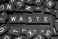 Black letter tiles spelling the word & x22;waste& x22; Royalty Free Stock Photo