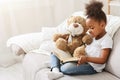 Black little girl reading fairy tale to her teddy bear Royalty Free Stock Photo