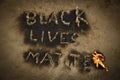 Black Lives Matter text slogan fire burn, human rights protest message revealed by black soot after fire flames