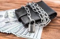 Black locked wallet by chain with padlock and money on the table