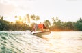 Black long-haired teen boy riding and jumping from a long surfboard. He caught a  wave in an Indian ocean bay with magic sunset Royalty Free Stock Photo