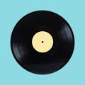 Black long-play vinyl record with yellow label isolated on cyan background front view close up