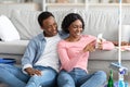 Black lovers with cleaning tools sitting on floor, using smartphone Royalty Free Stock Photo