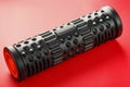Black lumpy foam massage roller on red background. For the mechanical and reflex effects on tissues and organs Royalty Free Stock Photo