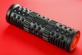 Black lumpy foam massage roller on red background. For the mechanical and reflex effects on tissues and organs Royalty Free Stock Photo