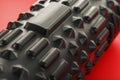 Black lumpy foam massage roller on red background. For the mechanical and reflex effects on tissues and organs Royalty Free Stock Photo