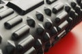 Black lumpy foam massage roller on red background. For the mechanical and reflex effects on tissues and organs Royalty Free Stock Photo
