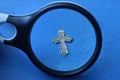 Black magnifier enlarges a small old gray silver cross Royalty Free Stock Photo