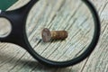 Black magnifier magnifies brown rusty screw Royalty Free Stock Photo