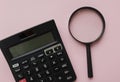 Top view and flat lay black magnifying glass and calculator on pink pastel background.Business and finanse concept