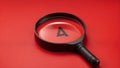 A black magnifying glass with a handle pointed at an object on a red background.