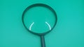 a black magnifying glass isolated on a solid teal background. Royalty Free Stock Photo