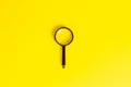 Black magnifying glass on light yellow background. Royalty Free Stock Photo