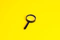 Black magnifying glass on light yellow background. Royalty Free Stock Photo