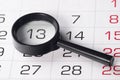 Black magnifying glass over calendar