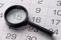 Black magnifying glass over calendar