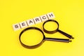 Black magnifying glass with the word search on light yellow background. Royalty Free Stock Photo
