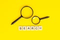 Black magnifying glass with the word search on light yellow background. Royalty Free Stock Photo