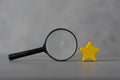 A black magnifying glass with a yellow star. The concept of finding the star, find a new actor. Hiring and recruitment selection