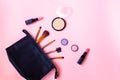 Black makeup bag with cosmetic beauty products and make-up brushes on pink background Royalty Free Stock Photo