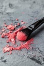 A black makeup brush with its bristles coated in orange powder