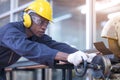 Black male african american workers wear sound proof headphones and yellow helmet working an iron cutting machine in background