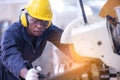 Black male african american workers wear sound proof headphones and yellow helmet working an iron cutting machine in background