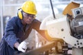 Black male african american workers wear sound proof headphones and yellow helmet working an iron cutting machine in background