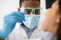 Black Male Dentist In Protective Mask And Face Shield Examining Patient& x27;s Teeth Royalty Free Stock Photo