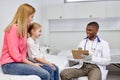 cheerful afro american male doctor listen consult cute caucasian girl make notes in patient card at medical checkup