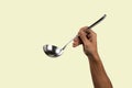 Black male hand holding a silver kitchen ladle isolated on green background Royalty Free Stock Photo